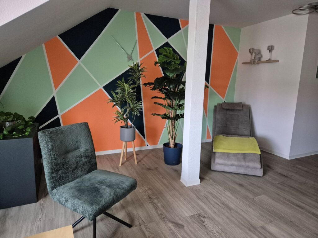 Praxisraum mit einer bunten Wand im Hintergrund